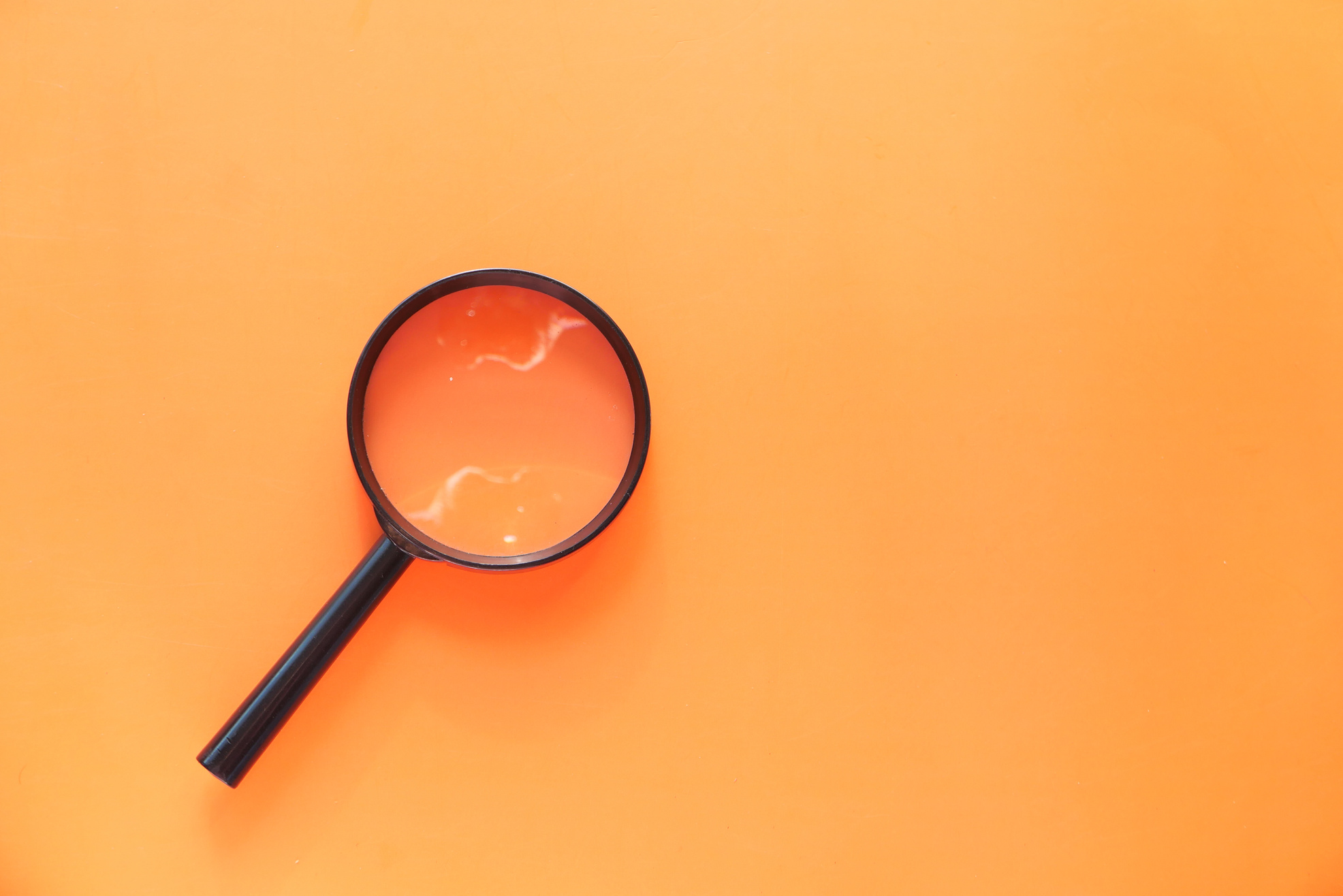 Top View of Magnifying Glass on Orange Background